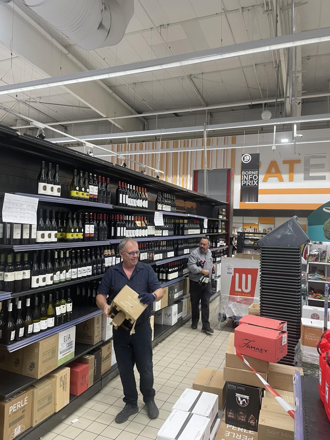 Travailleurs dans un supermarché avec des bouteilles de vin